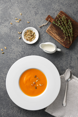 Pumpkin soup in a white big plate on gray stone backgroundの写真素材