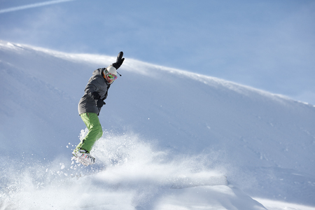 Young snowboarder jumping against snow slope backgroundの写真素材