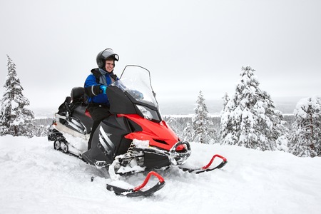 Happy smiling man driving snowmobile in Finnish Laplandの写真素材