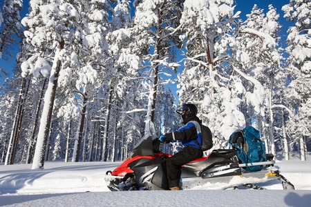 Man driving snowmobile in snowy forest in a sunny day. Lapland, Finland.の写真素材