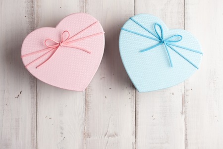 Pink and blue heart shaped gift boxes on white wooden backgroundの写真素材