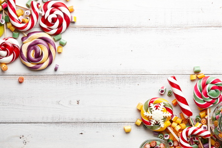 Colorful lollipops, candy canes and sweet candies mix on white wooden backgroundの写真素材