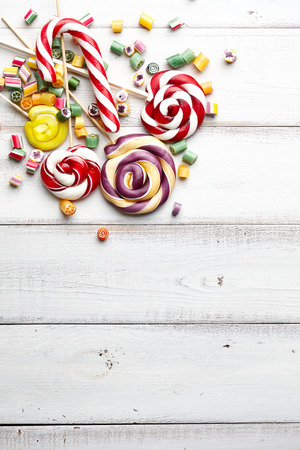 Colorful lollipops, candy canes and sweet candies mix on white wooden backgroundの写真素材