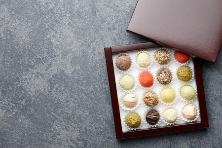 Various chocolate truffle candies in a box on gray stone backgroundの写真素材