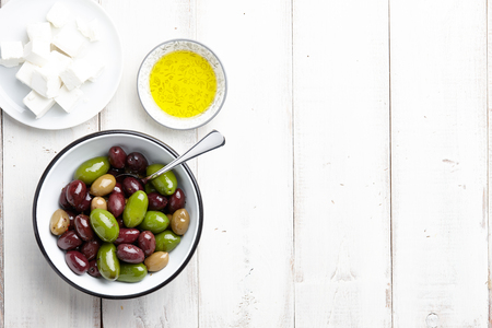 Fresh olives, feta cheese and olive oil on white wooden backgroundの写真素材