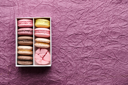 Box of colorful macarons on creased paper textured background, space for textingの写真素材