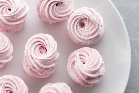 Pink homemade zephyr or marshmallow in white plate on light gray stone backgroundの写真素材