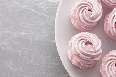 Pink homemade zephyr or marshmallow in white plate on light gray stone backgroundの写真素材