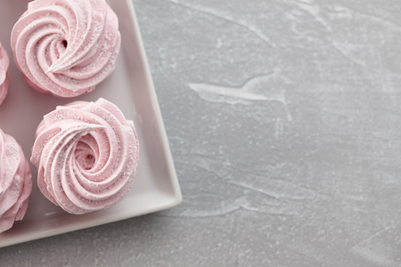 Pink homemade zephyr or marshmallow in white plate on light gray stone backgroundの写真素材