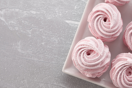 Pink homemade zephyr or marshmallow in white plate on light gray stone backgroundの写真素材