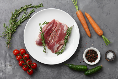 Raw duck breast in white plate with vegetablesの写真素材