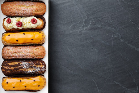 Box of different french eclairs: chocolate, salted caramel, raspberry and passion fruitの写真素材