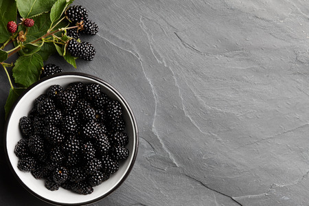 Bowl of fresh ripe blackberries on textured stone backgroundの写真素材