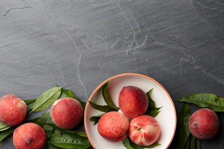 Fresh peaches fruits with leaves on textured stone background, top viewの写真素材
