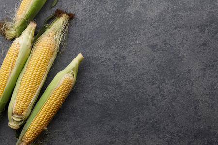 Sweet corns in wooden tray on a stone textured background, top viewの写真素材