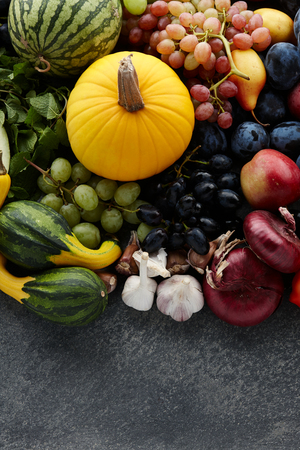 Autumn harvest concept. Seasonal fruits and vegetables on a stone tabletop, top viewの写真素材