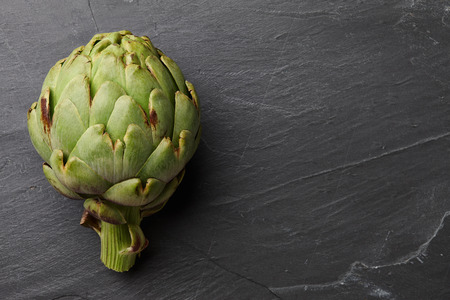 Fresh ripe artichokes close up on textured stone background, top viewの写真素材