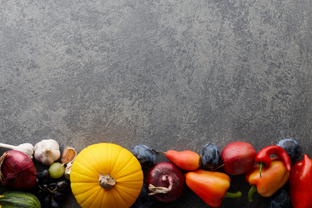 Autumn harvest concept. Seasonal fruits and vegetables on a stone tabletop, top viewの写真素材
