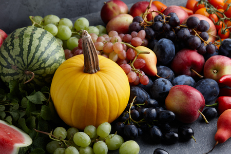 Autumn harvest concept. Seasonal fruits and vegetables on a stone tabletop, top viewの写真素材