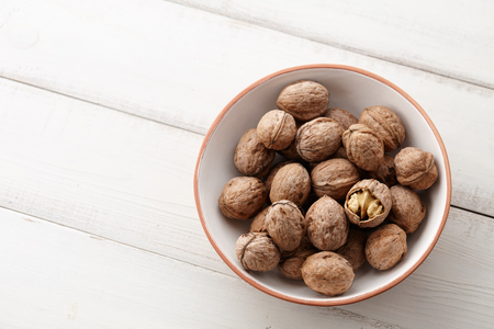Fresh walnuts bowl on white wooden background, space for textingの写真素材