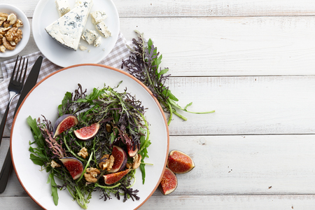 Salad with figs, blue cheese, arugula, mizuna and walnuts on white wooden background, top viewの写真素材
