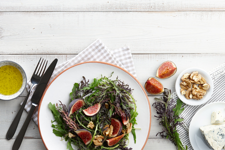 Salad with figs, blue cheese, arugula, mizuna and walnuts on white wooden background, top viewの写真素材