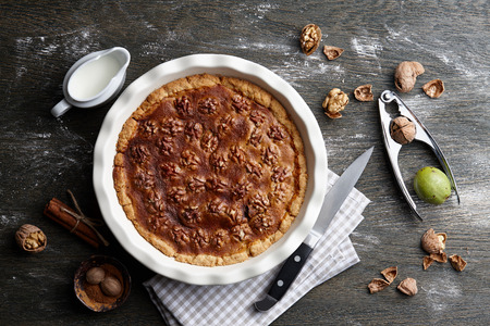 Traditional walnut pie, spices, nuts and nutcracker on dark wooden table, top viewの写真素材