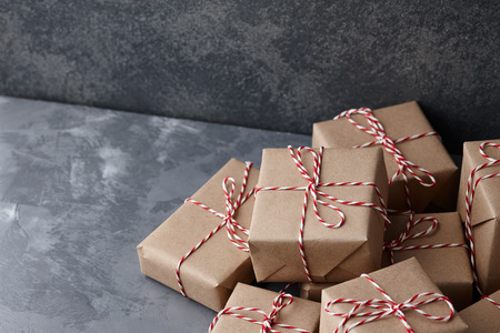 Christmas gift or present boxes wrapped in kraft paper with striped bakers twine string on textured stone background, copy spaceの写真素材