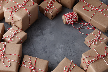 Christmas gift or present boxes wrapped in kraft paper with striped baker's twine string on textured stone background, copy spaceの写真素材