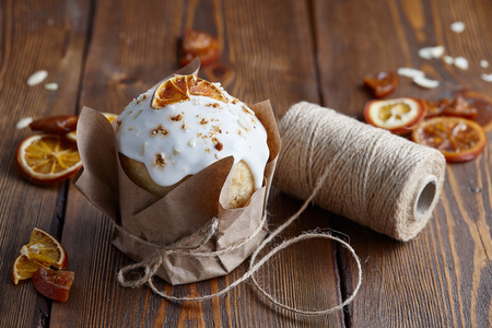 Easter cakes with candied fruits and almond crumbs wrapped in kraft paper on brown wooden table