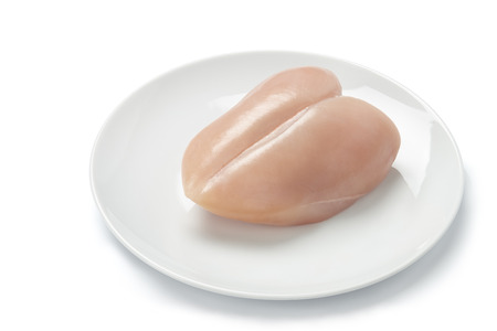 Raw chicken breast in white plate isolated on white backgroundの写真素材