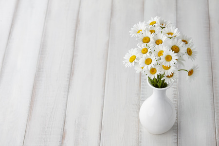 Chamomiles or daisies in white vase on wooden planks, summer flowers compositionの写真素材