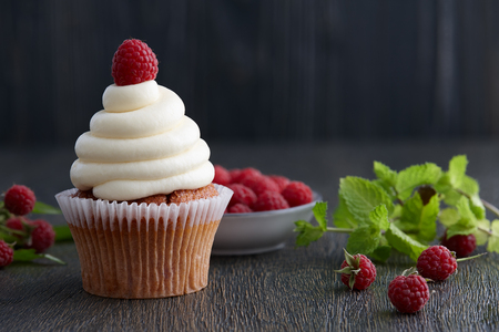 Beautiful cupcakes with fresh raspberries on dark wooden backgroundの写真素材