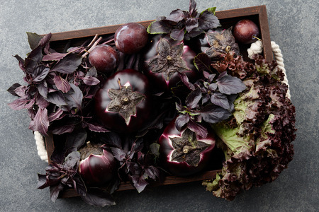 Wooden tray with purple vegetables and herbs on stone textured backgroundの写真素材