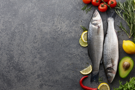 Fresh raw seabass and ingredients for cooking: rosemary, thyme, lime, lemon, etc. Top view copyspaceの写真素材