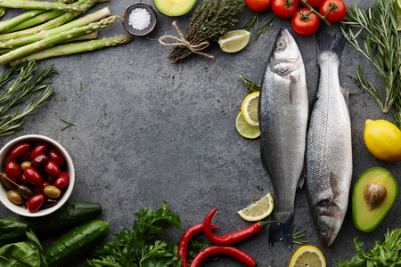 Fresh raw seabass and ingredients for cooking: rosemary, thyme, lime, lemon, etc. Top view copyspaceの写真素材