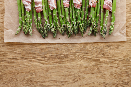 Raw green asparagus wrapped with bacon ready for baking, top viewの写真素材