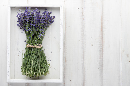 Beautiful lavender flowers bouquet in white wooden tray on planks, top viewの写真素材