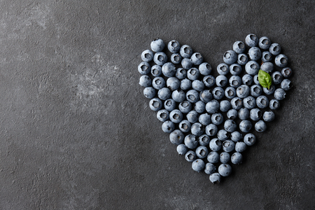 Fresh blueberries heart shape on black background. Healthy food eating concept.の写真素材