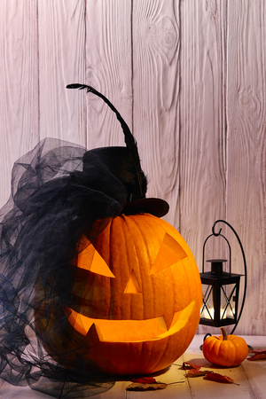 Halloween pumpkin head jack lantern with black bride hat in dark barn, holiday conceptの写真素材