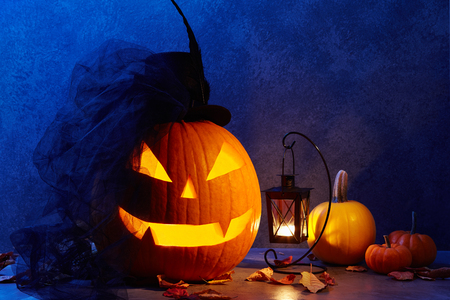 Halloween pumpkin head jack lantern with black bride hat in dark barn, holiday conceptの写真素材