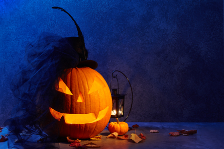 Halloween pumpkin head jack lantern with black bride hat in dark barn, holiday conceptの写真素材
