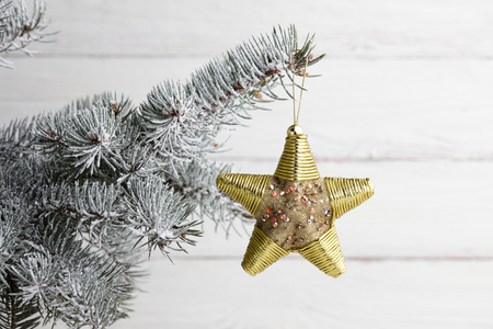 Christmas tree golden star toy hanging on snowy fir branch, holiday decorationの写真素材