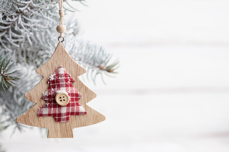 Wooden tree-shaped Christmas toy hanging on snowy fir branch, copy spaceの写真素材