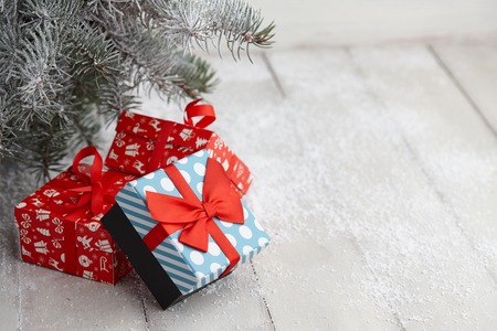 Christmas gift boxes with festive patterns and ribbons under snowy fir tree, copy spaceの写真素材