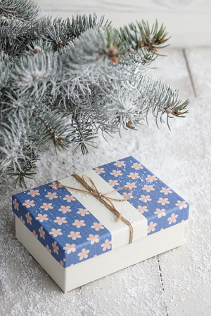 Christmas gift box with festive pattern under snowy fir tree, copy spaceの写真素材