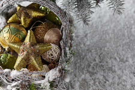 Wicker basket with Christmas gifts, toys and holiday decorations under snowy fir tree, copy spaceの写真素材
