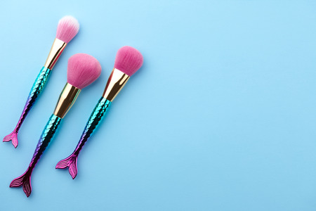 Fish shape glossy make up brushes close up on blue backgroundの写真素材