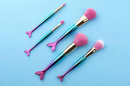 Fish shape glossy make up brushes close up on blue backgroundの写真素材