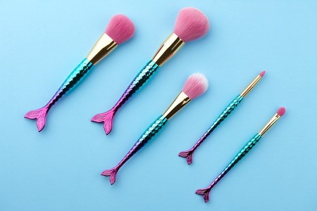 Fish shape glossy make up brushes close up on blue backgroundの写真素材